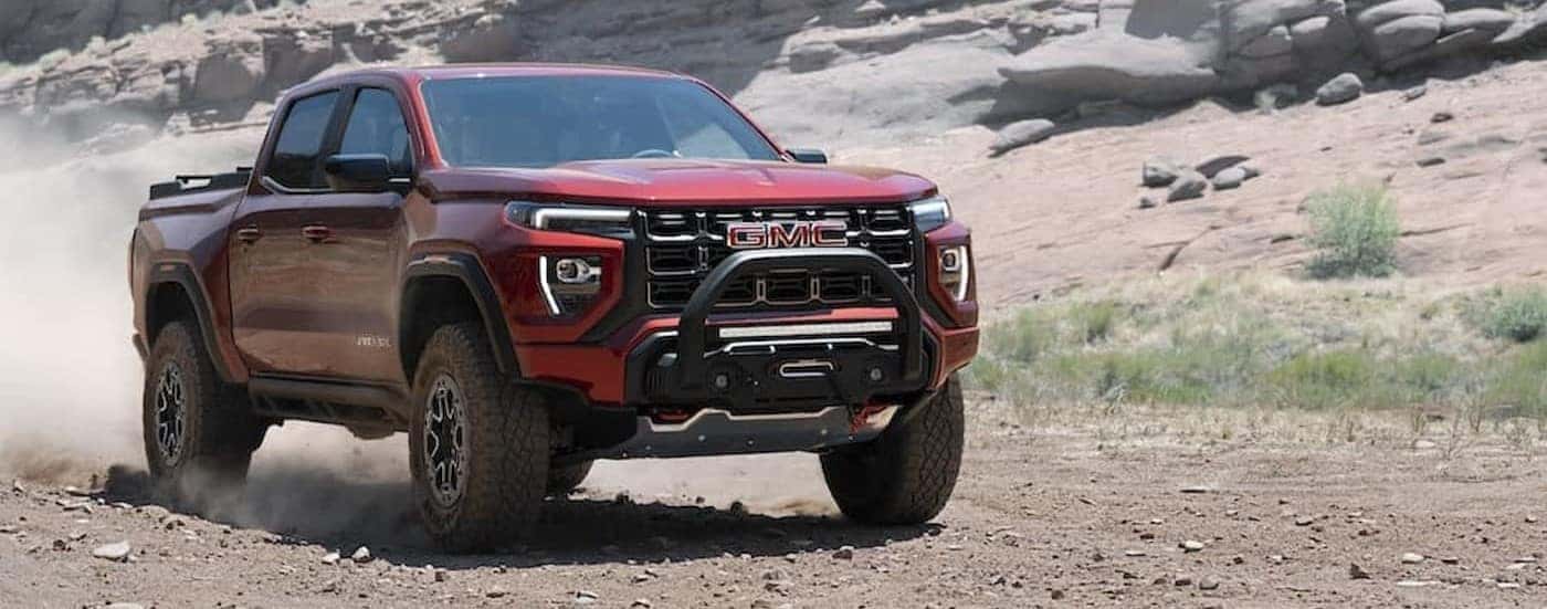A red 2023 GMC Canyon AT4 driving down a desert road