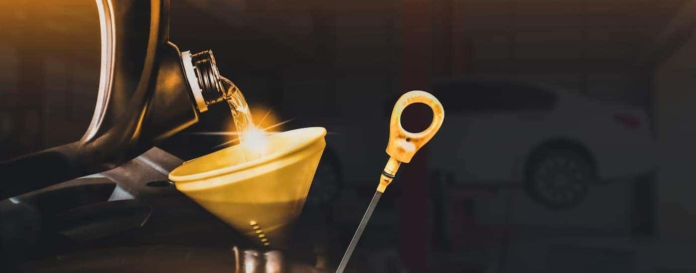 A dipstick near oil being poured into a funnel.