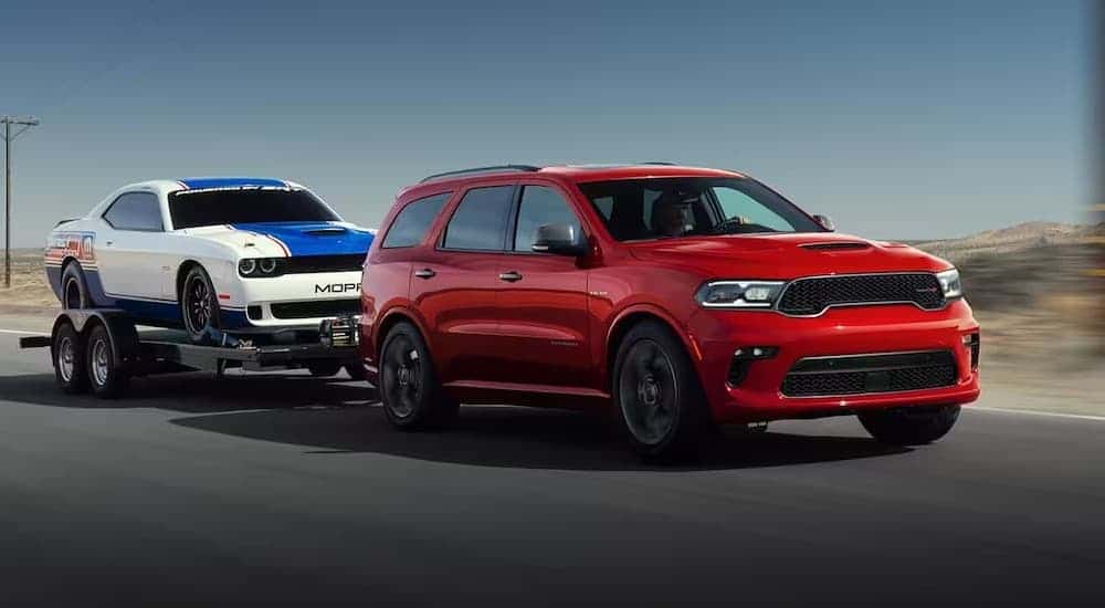 A red 2023 Dodge Durango towing a trailer to a used car dealership.