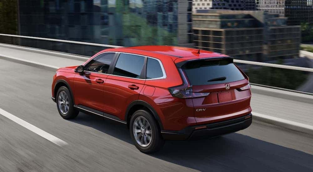 A red 2023 Honda CR-V driving on a bridge.