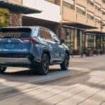A blue 2024 Toyota RAV4 driving to view used SUVs for sale.