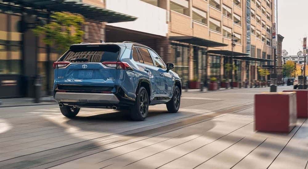 A blue 2024 Toyota RAV4 driving to view used SUVs for sale.