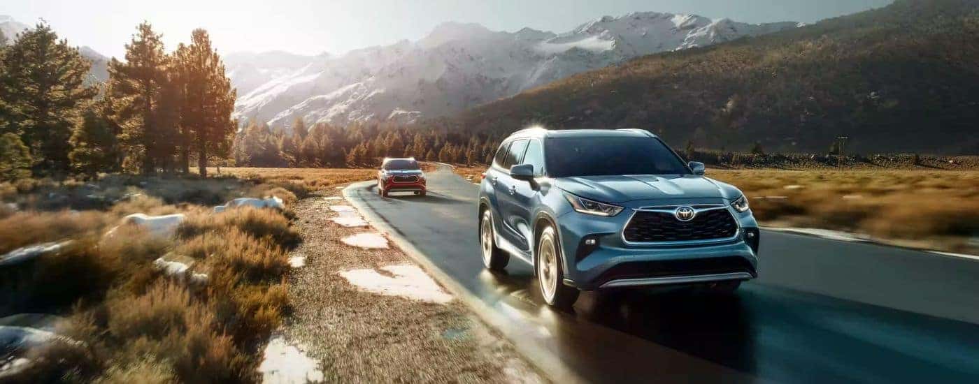 Two 2023 Toyota Highlanders driving outdoors on a backroad.