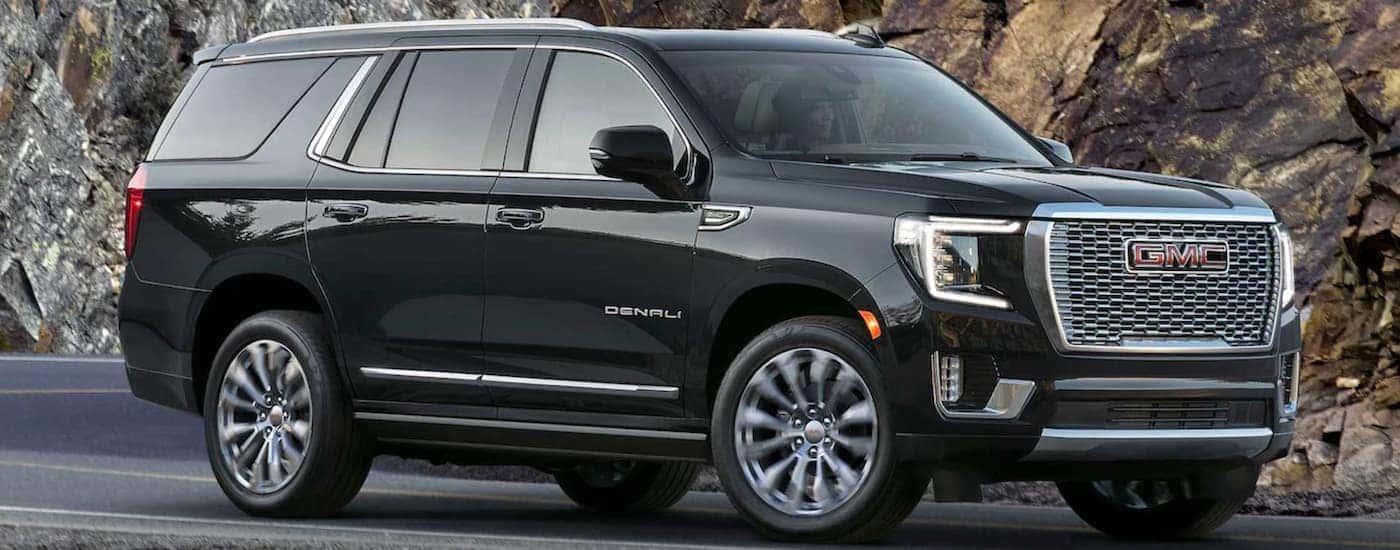 A black 2023 GMC Yukon Denali driving on a highway.