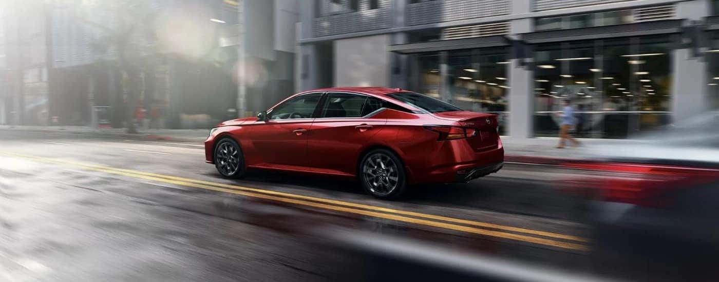 A red 2023 Nissan Altima driving in a city