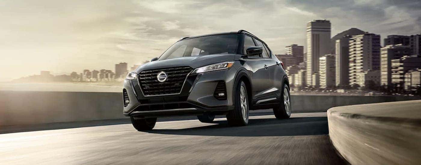 Grey 2021 Nissan Kicks driving down a city street away from a city
