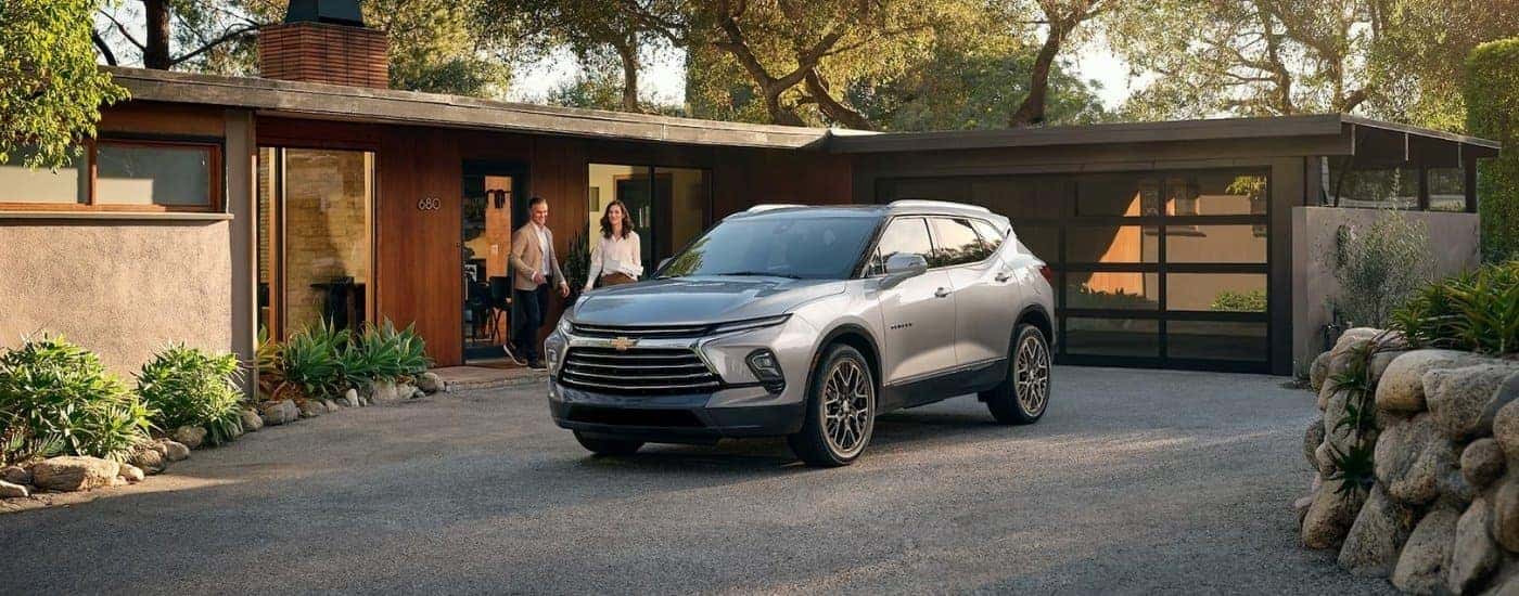 Two people approaching a silver 2025 Chevy Blazer parked on a driveway