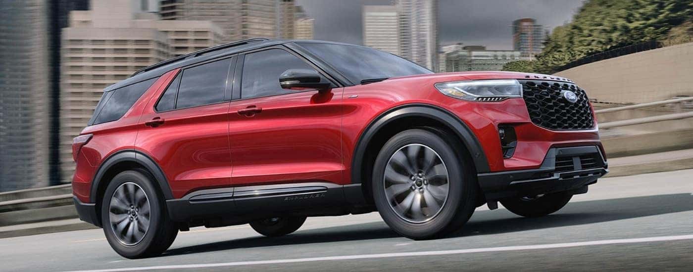 A red 2025 Ford Explorer ST-Line driving up a hill in a city