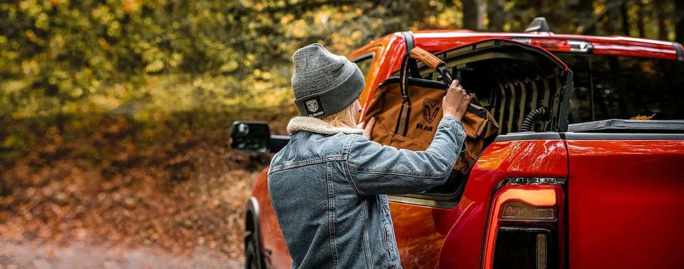 A woman opening the side storage box on a red 2022 Ram 1500