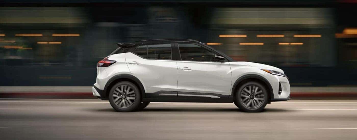 White 2024 Nissan Kicks driving in a city from a side angle