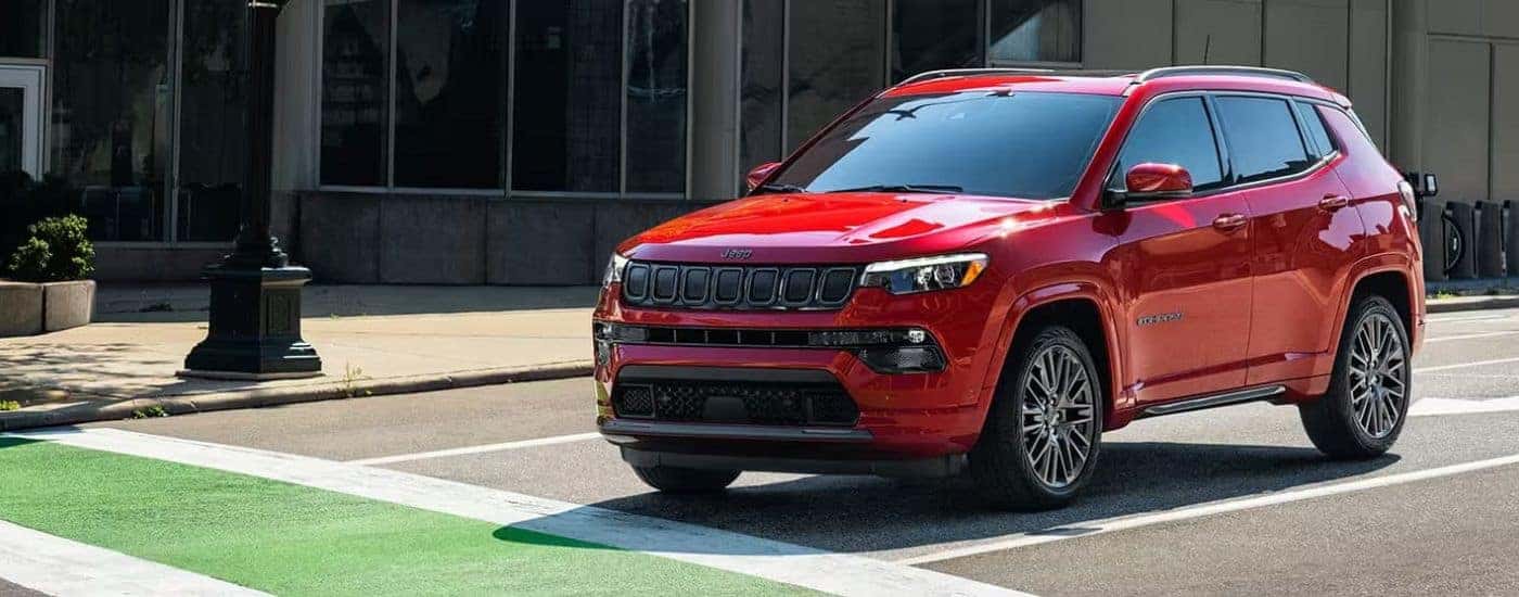 A red 2023 Jeep Compass stopped at a crosswalk