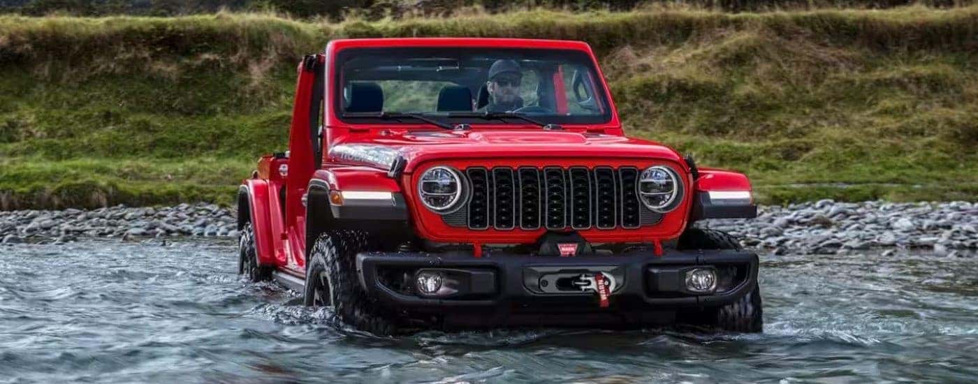 A red 2024 Jeep Wrangler driving offroad.