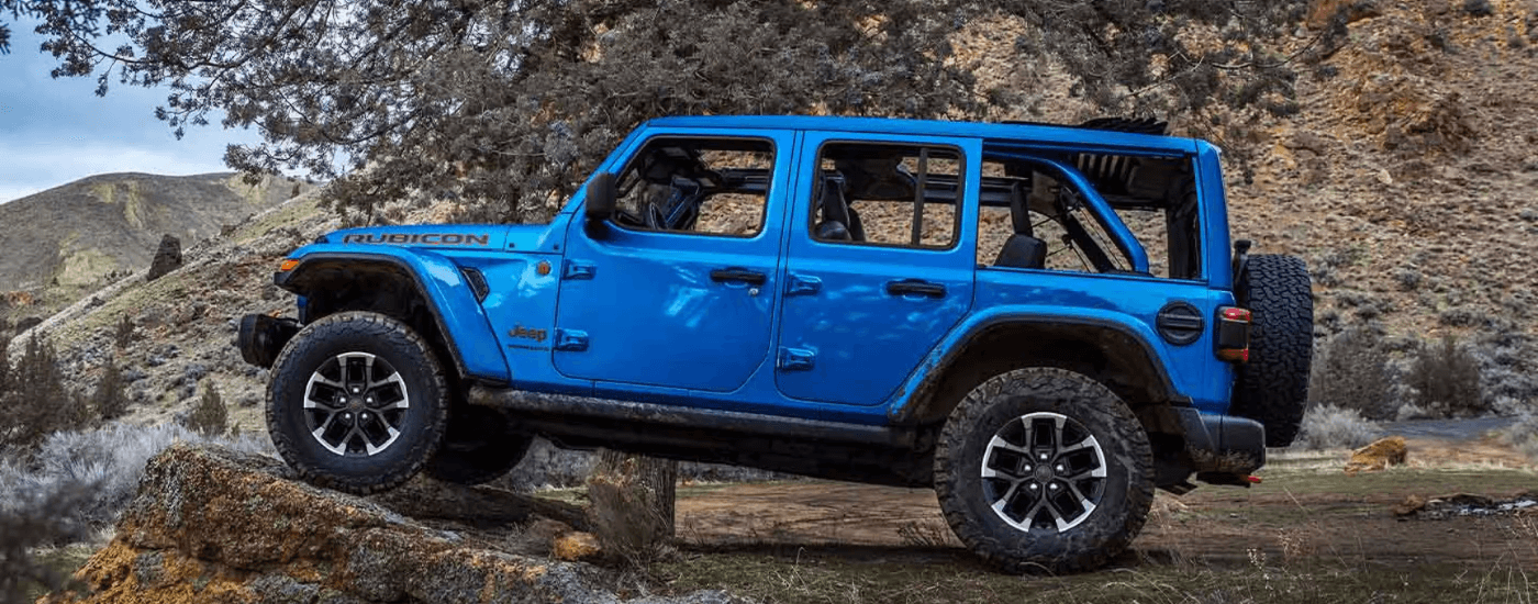 A blue 2025 Jeep Wrangler Rubicon parked on a rock formation off-road