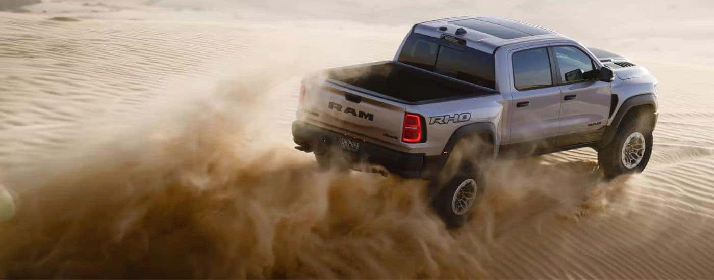 Silver 2025 Ram 1500 RHO driving across a sand dune