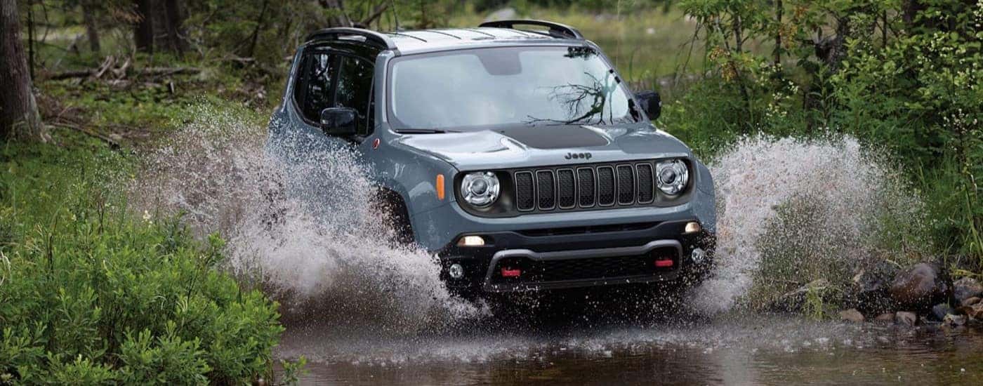 A light blue 2023 Jeep Renegade Trailhawk driving through a puddle.