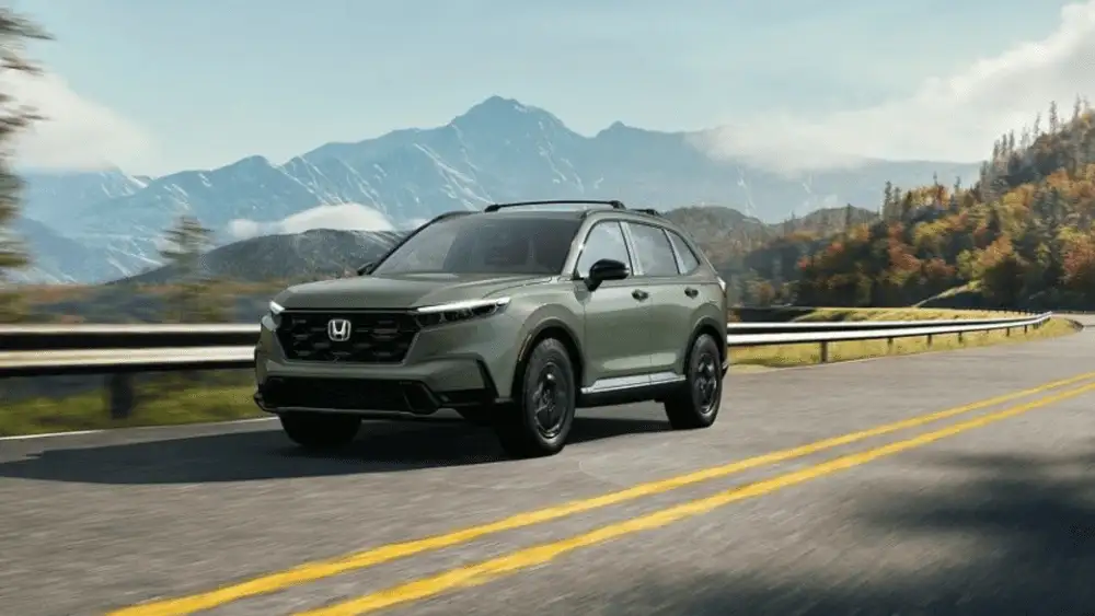 2026 Honda CR-V Hybrid near Smithtown NY driving on a scenic highway with mountains, showing smooth long drive efficiency