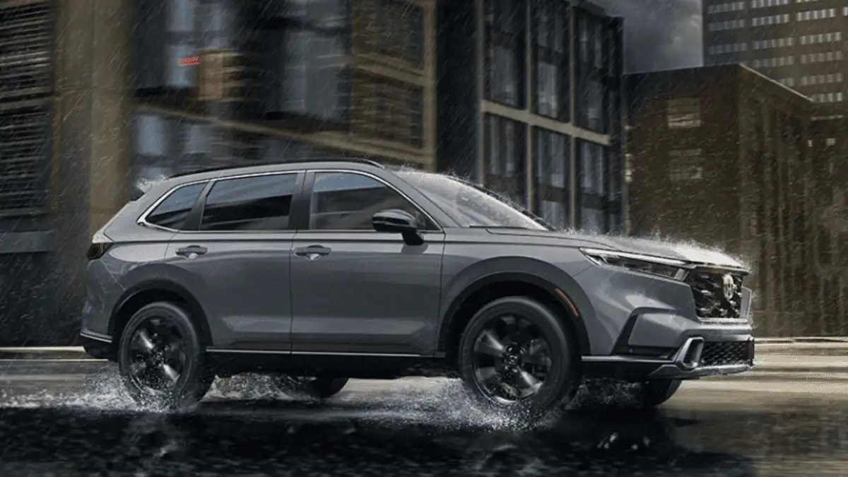 2026 Honda CR-V Hybrid near Smithtown, NY, SUV driving through rainy city streets with water splashing around the wheels