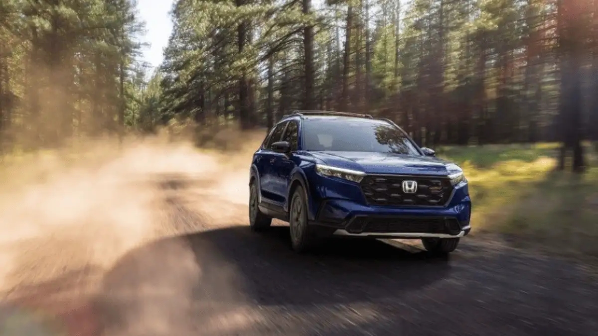 2026 Honda CR-V near Smithtown, NY, blue SUV driving on a forest dirt road with dust trail and sunlit trees