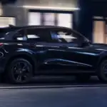2026 Honda HR-V near Smithtown NY in side profile driving past city storefronts at night, compact SUV for first time buyers