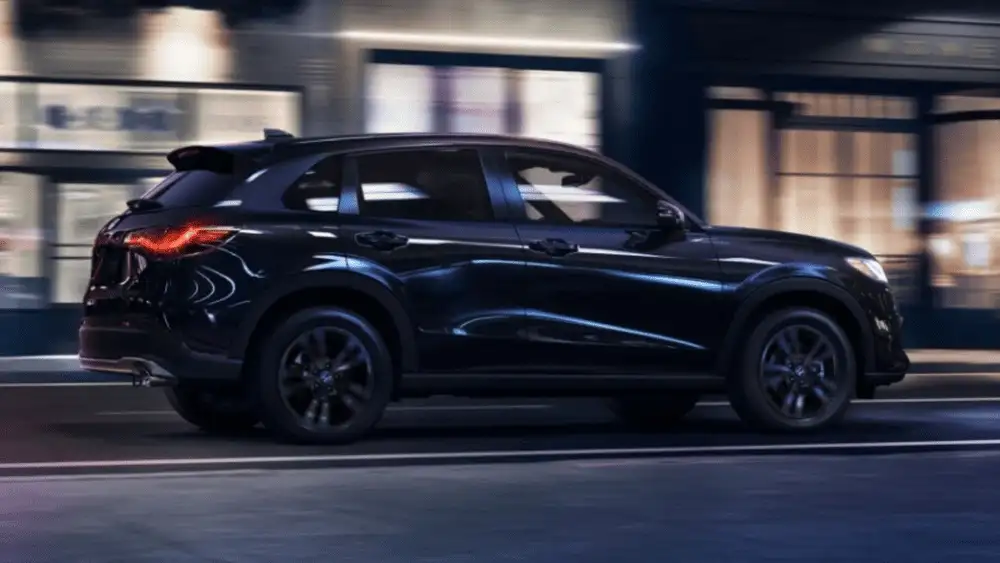 2026 Honda HR-V near Smithtown NY in side profile driving past city storefronts at night, compact SUV for first time buyers