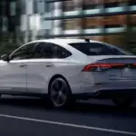 2026 Honda Accord Hybrid near Smithtown NY driving in the city, rear three quarter view highlighting fuel saving commuter performance