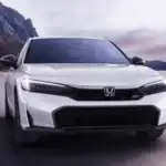 2026 Honda Civic Si near Smithtown, NY driving on an open highway, featuring a sporty front view and performance-focused styling.
