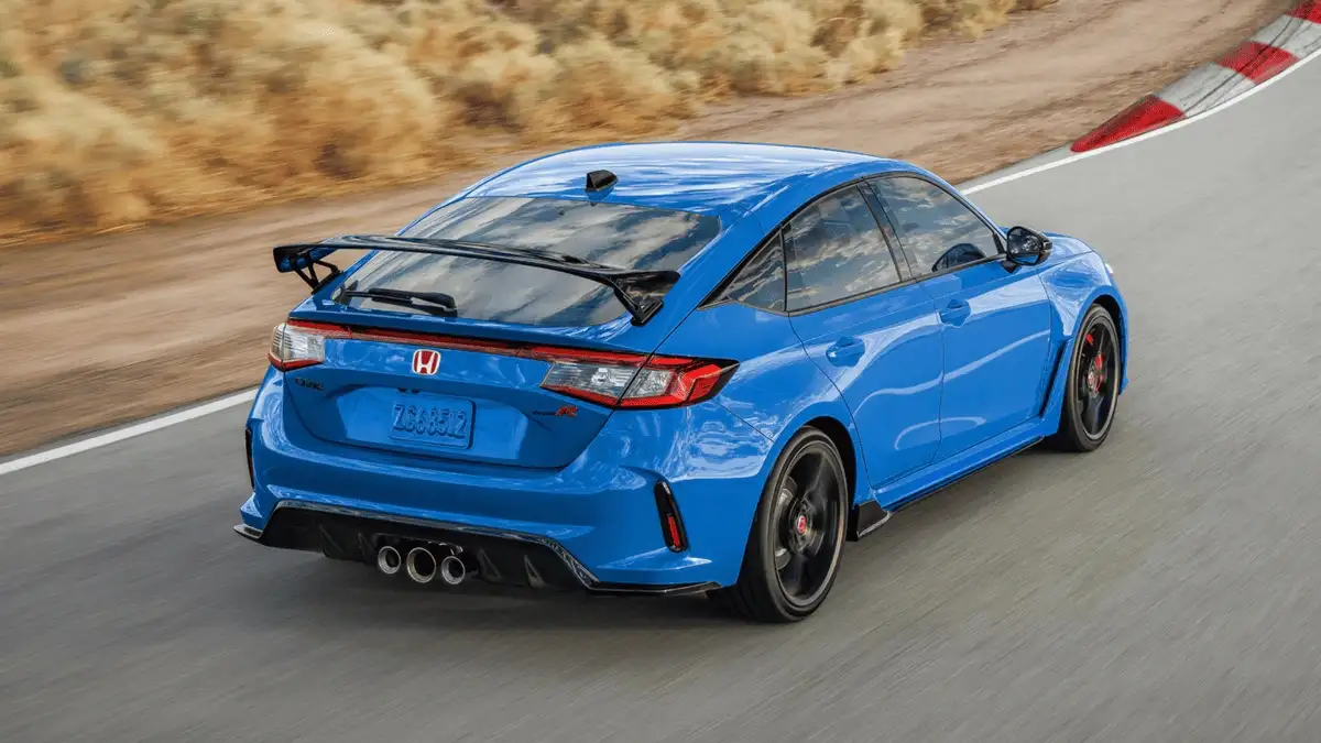 2025 Honda Civic Type R near Smithtown, NY blue hatchback speeding on a racetrack, rear three-quarter view with big wing spoiler