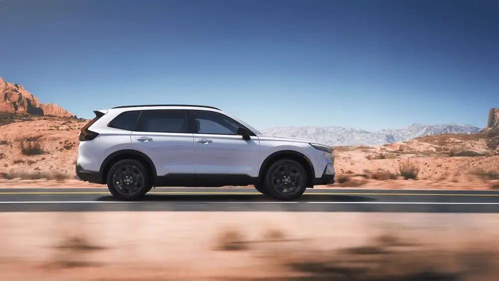 2026 Honda CR-V Hybrid in Platinum White Pearl side profile driving on desert highway near Commack NY
