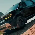 2026 Honda Ridgeline in Radiant Red Metallic front three-quarter view on rocky mountain terrain — comparing work trucks near Commack NY
