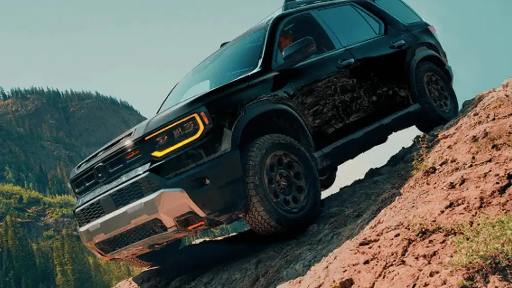 2026 Honda Ridgeline in Radiant Red Metallic front three-quarter view on rocky mountain terrain — comparing work trucks near Commack NY
