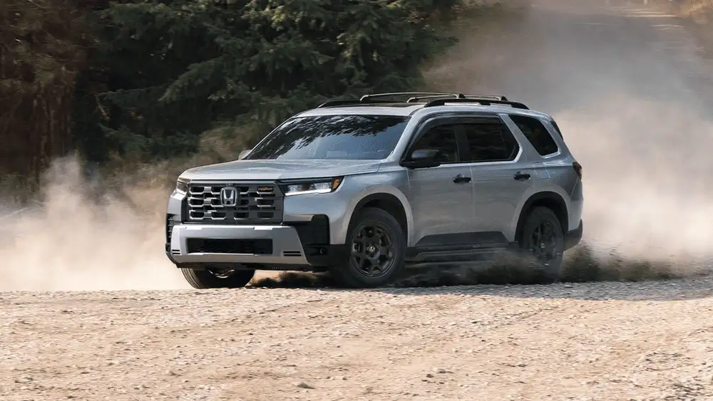 2025 Honda Pilot in Lunar Silver Metallic TrailSport front three-quarter view on dusty gravel road — best scenic drives near Commack NY