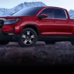 2026 Honda Ridgeline in Radiant Red Metallic front three-quarter view on rocky mountain terrain — comparing work trucks near Commack NY