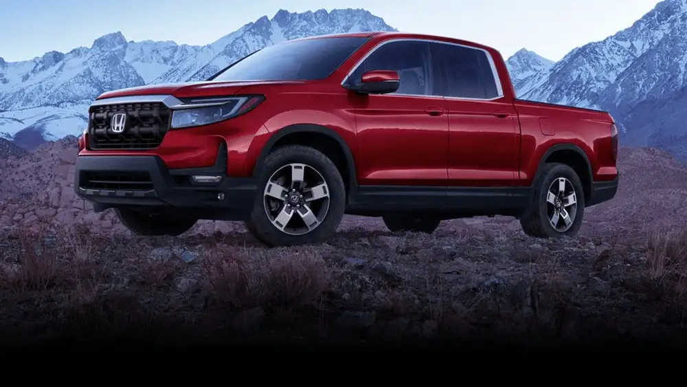 2026 Honda Ridgeline in Radiant Red Metallic front three-quarter view on rocky mountain terrain — comparing work trucks near Commack NY