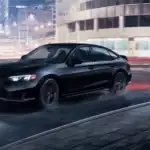 2026 Honda Civic Si in Crystal Black Pearl front three-quarter view driving on wet city road at night near Commack NY