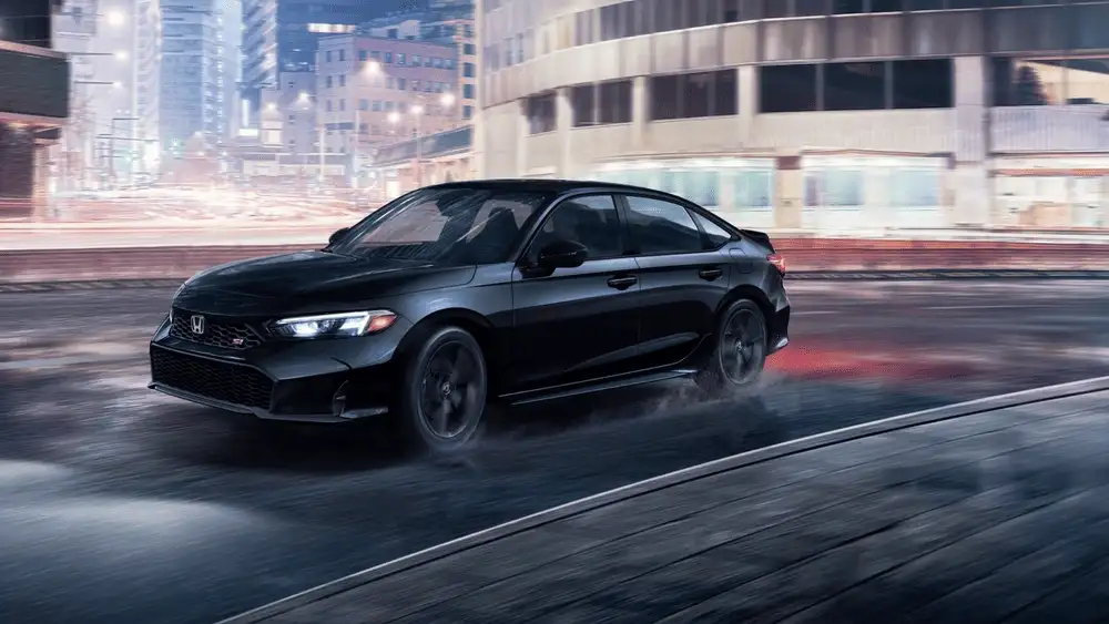 2026 Honda Civic Si in Crystal Black Pearl front three-quarter view driving on wet city road at night near Commack NY