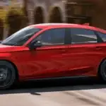 Red 2026 Honda Civic Hatchback Hybrid driving through town, showing off its cargo space advantages near Commack