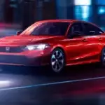 Red 2026 Honda Civic Sedan Hybrid driving through the city at night, highlighting family friendly benefits near Commack