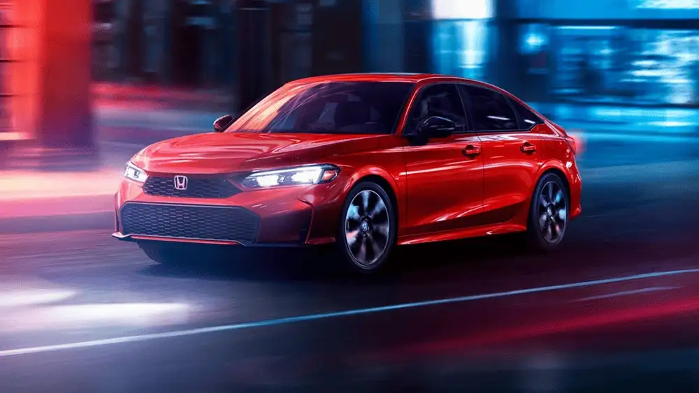 Red 2026 Honda Civic Sedan Hybrid driving through the city at night, highlighting family friendly benefits near Commack