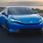 Blue 2026 Honda Prelude Hybrid cruising along a coastal highway at sunset, compared to competitors near Commack