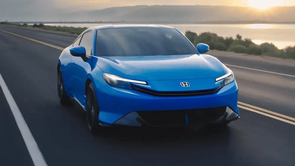 Blue 2026 Honda Prelude Hybrid cruising along a coastal highway at sunset, compared to competitors near Commack