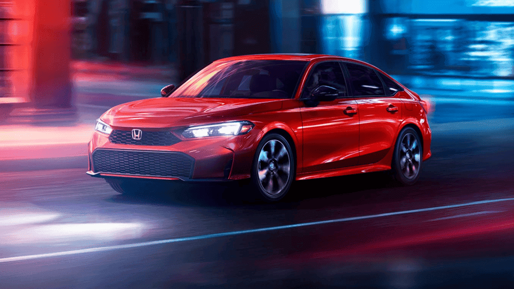 Red 2026 Honda Civic Sedan driving through a neon-lit city street at night near Hauppauge NY
