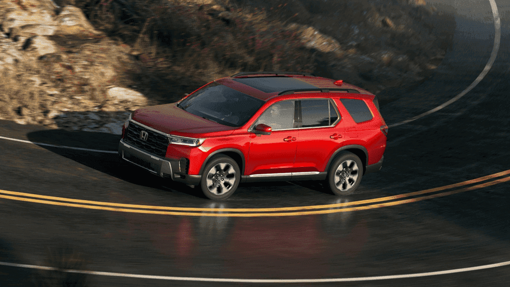 Red 2026 Honda Pilot taking a sharp curve on a mountain road near Hauppauge NY
