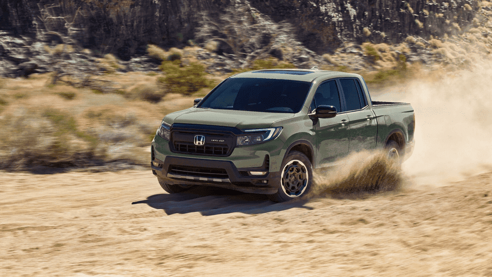 Olive green 2026 Honda Ridgeline pickup truck kicking up dust on a desert road near Hauppauge NY