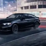 Black 2026 Honda Civic Si near Hauppauge, NY, driving through a city street at night.