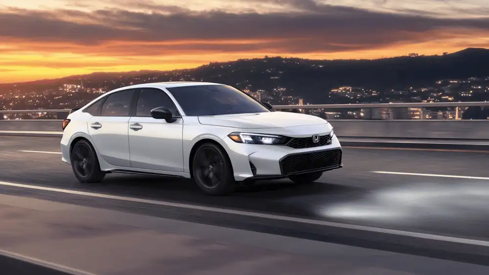 White 2026 Honda Civic Si near Hauppauge, NY, driving on a road at sunset.