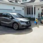 Gray 2026 Honda Odyssey near Hauppauge, NY, parked in a driveway with a family walking toward it.