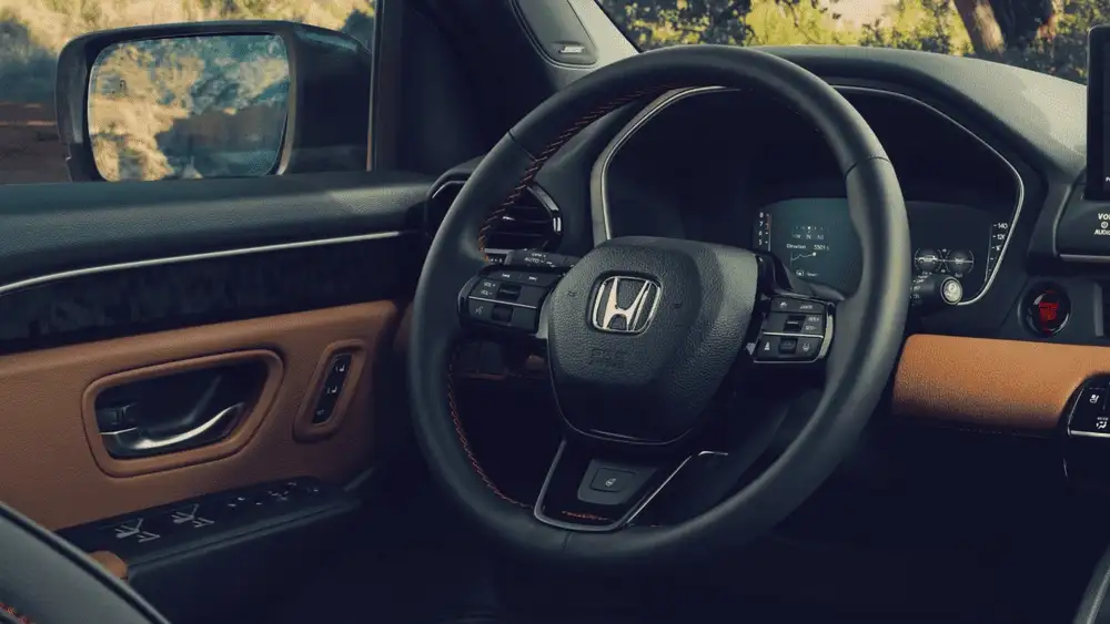 Black and tan interior of a 2026 Honda Passport near Hauppauge, NY, showing the steering wheel and door panel.