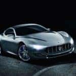 silver Maserati Alfieri sports car as a concept car parked on cracked pavement in a dark room with its LED headlights turned on