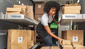 woman placing brown box on shelf in van