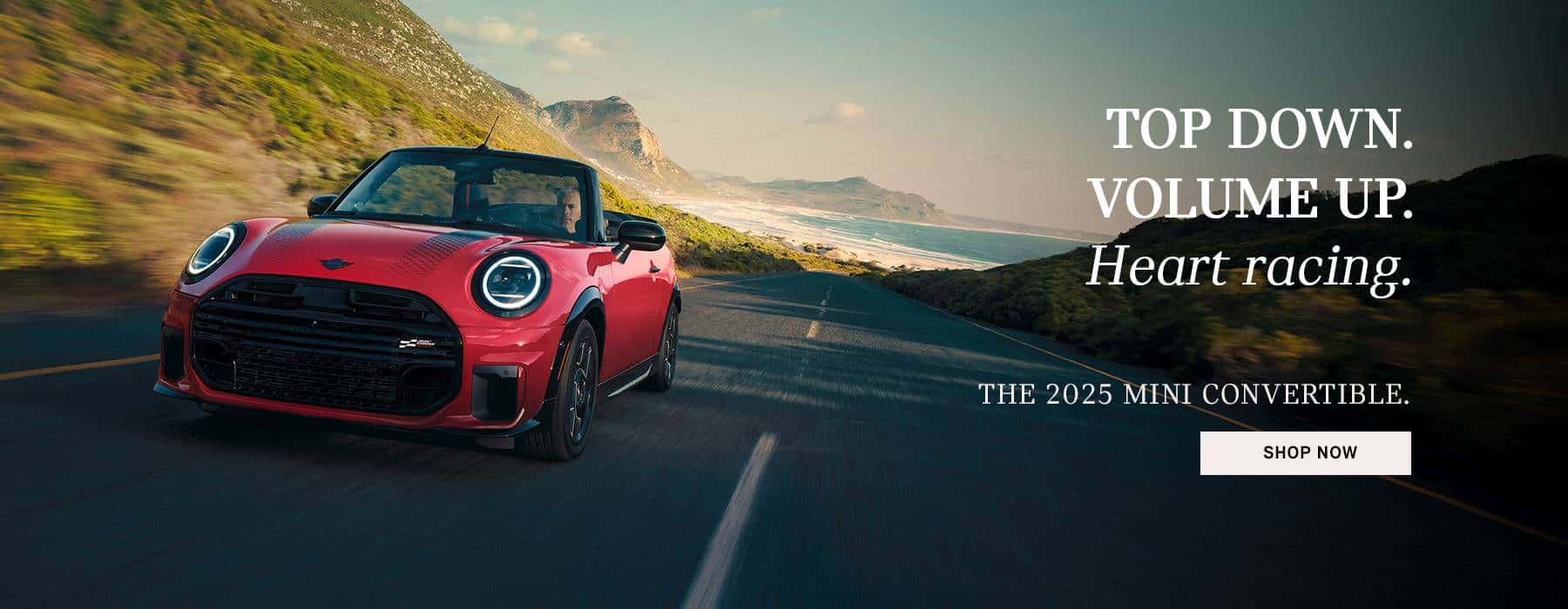 Red MINI JCW Convertible driving through mountains.
